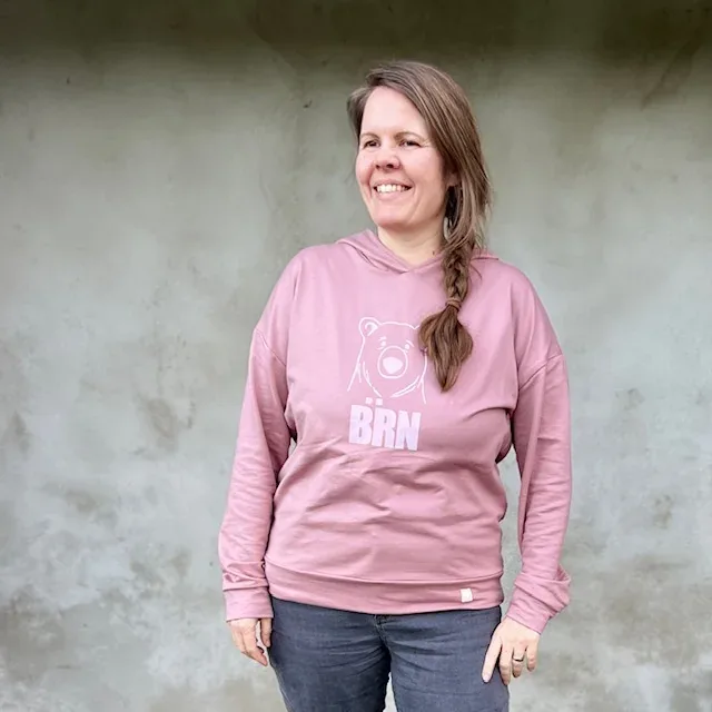Romi in einem altrosa Hoodie mit weissem Bärenkopf und Bärn-Schriftzug
